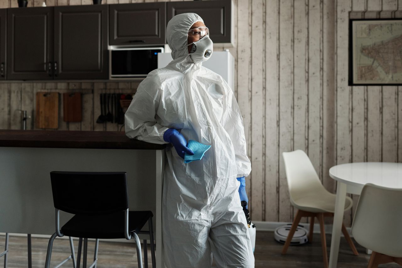 project-01-d A person in full PPE gear standing indoors, emphasizing disinfection during COVID-19.