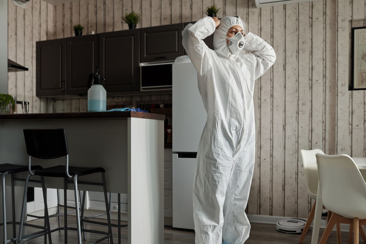 Individual in protective gear standing in a contemporary kitchen setting during the day.